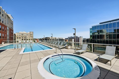 A swimming pool on a rooftop with chairs around it.
