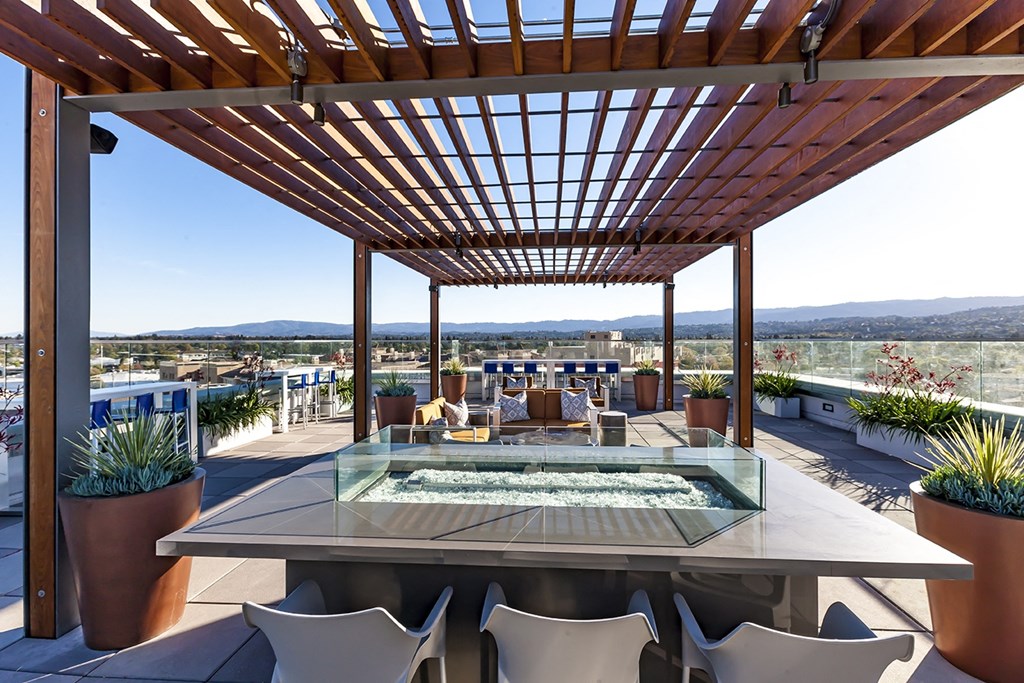 a patio with a table and chairs under a wooden roof