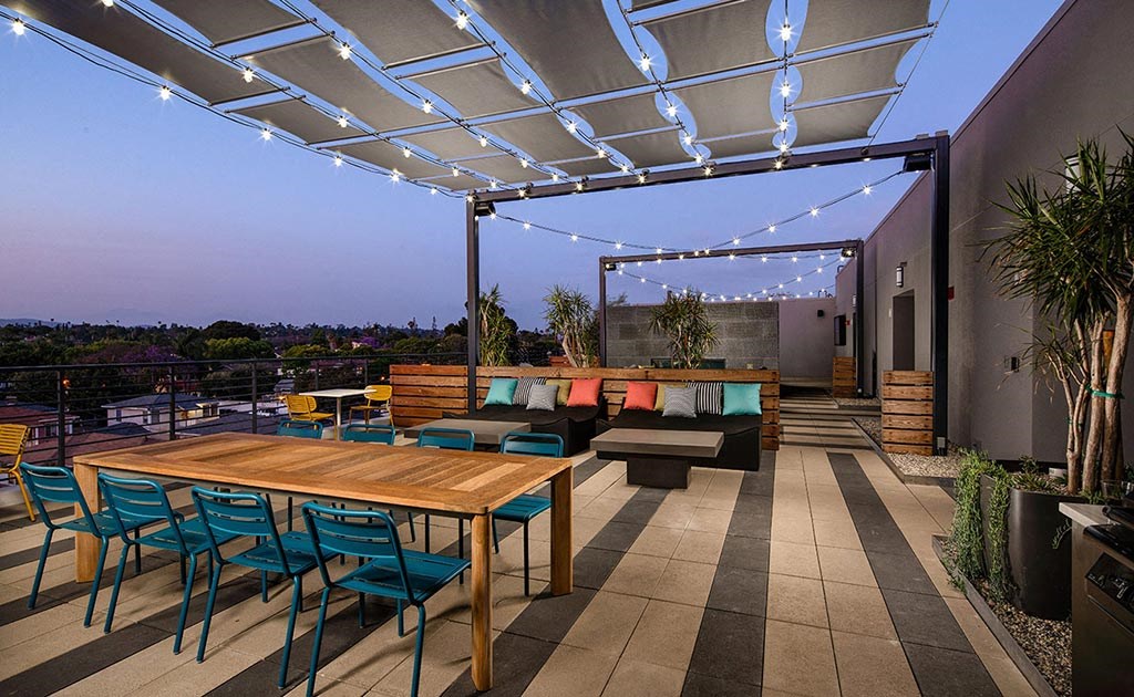 a patio with a wooden table and chairs under a roof