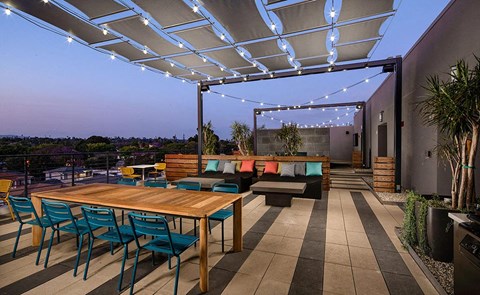 a patio with a wooden table and chairs under a roof
