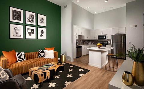 an apartment living room with a green wall and a kitchen
