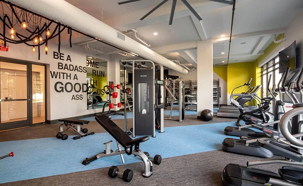a gym with weights and cardio equipment and a poster on the wall