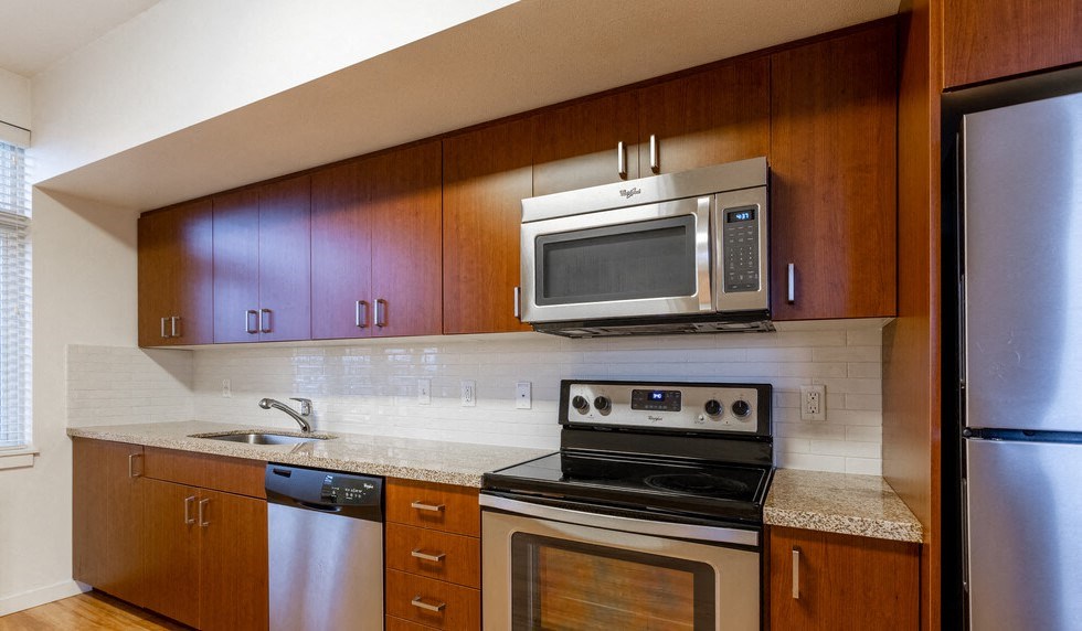 Nob Hill Portland, OR Apartments - The Cordelia - Upgraded Kitchen with Granite Countertops, Stainless Steel Appliances, and Wood Cabinetry