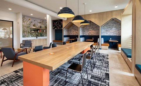 a long wooden communal table in a room with chairs