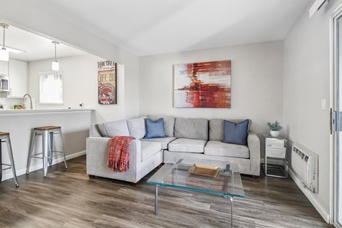 A living room with a white couch and a red and white painting on the wall.