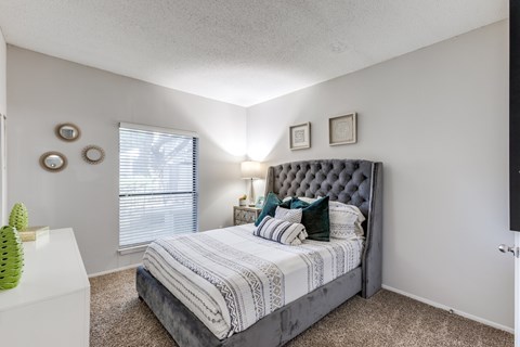 A bedroom with a large bed and a window with blinds.