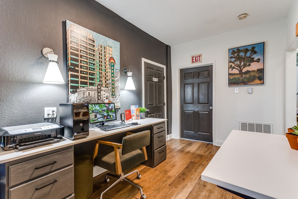 a desk with a computer and a printer in a room with a door that is open