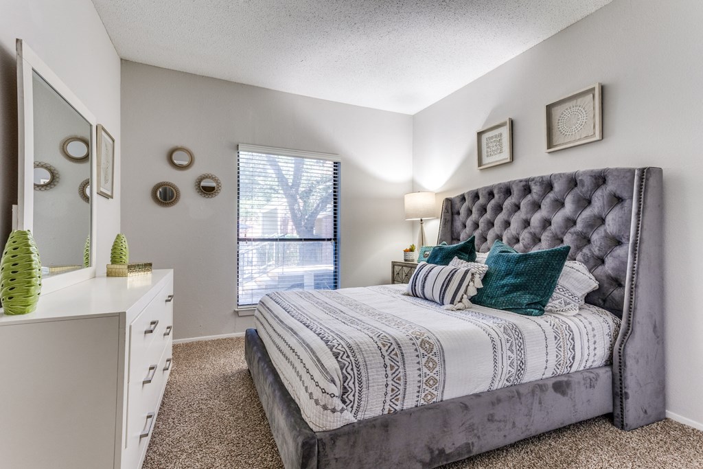 a bedroom with a large bed and a dresser with a mirror