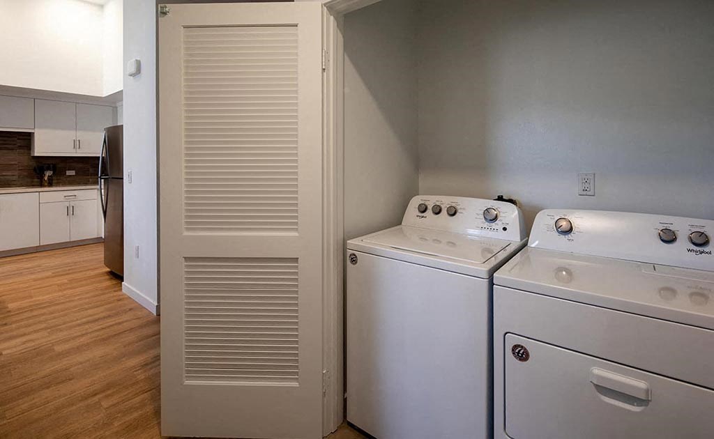 a kitchen with two washer and dryers and a door