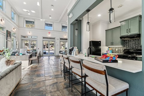 A kitchen with a long counter and chairs.