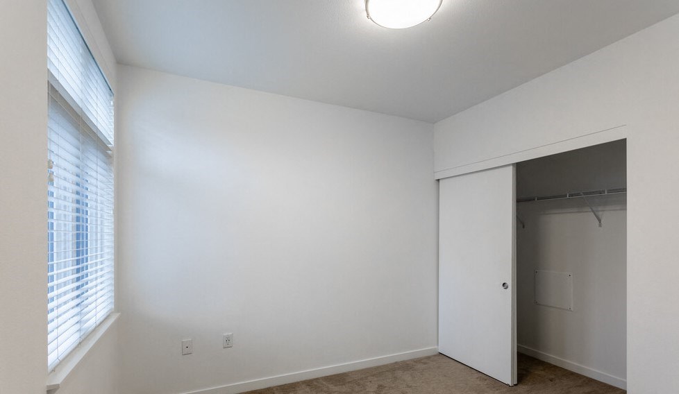 Studio Apartments in Nob Hill, Portland, OR - The Cordelia - Bedroom with Sliding Closet Door, Carpeting, a Window, and a Ceiling Light