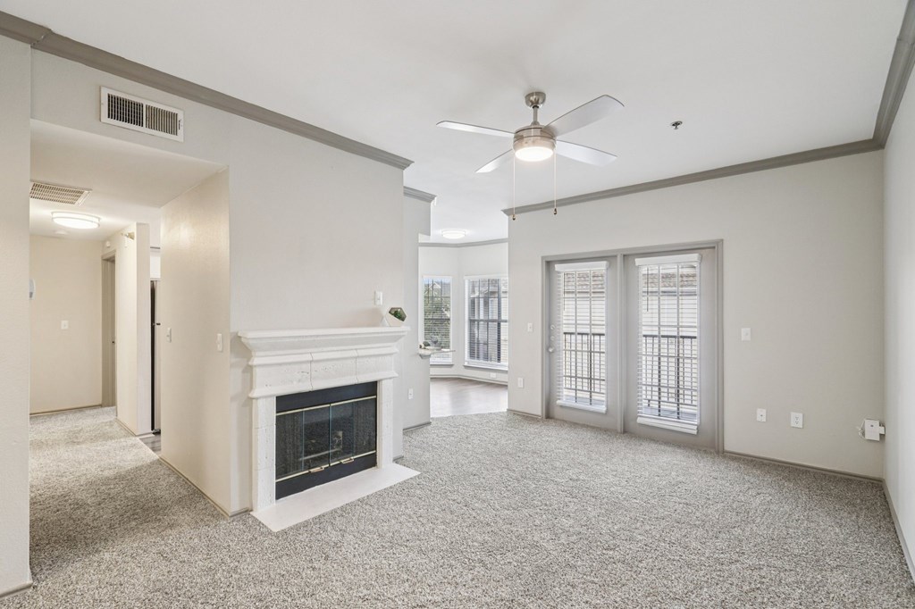 A living room with a fireplace and a ceiling fan.
