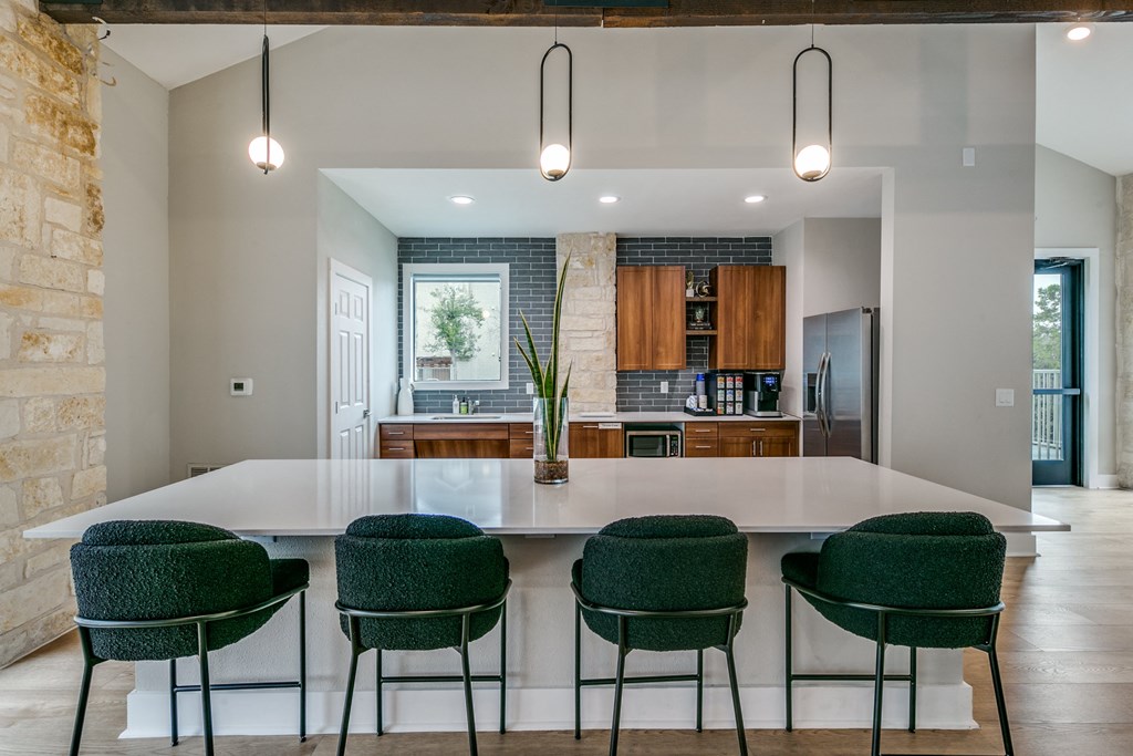 a kitchen with a large white island and green chairs at Canyon Ridge, Austin