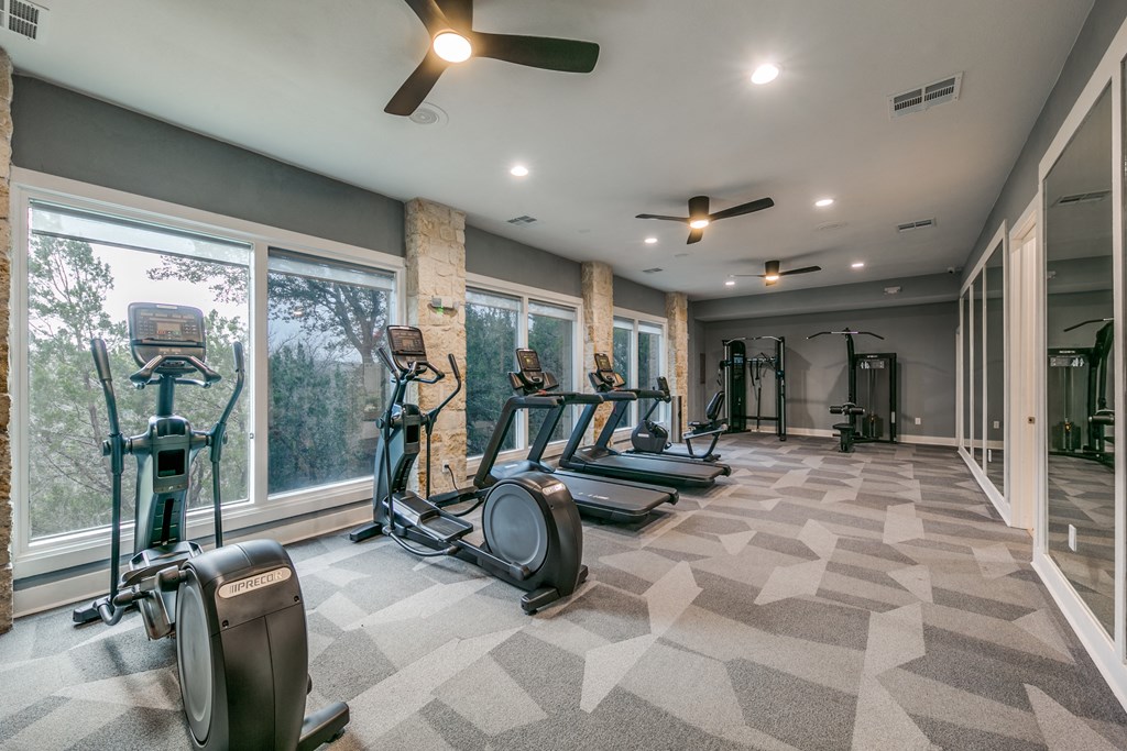 the gym has plenty of cardio equipment and large windows at Canyon Ridge, Austin, Texas