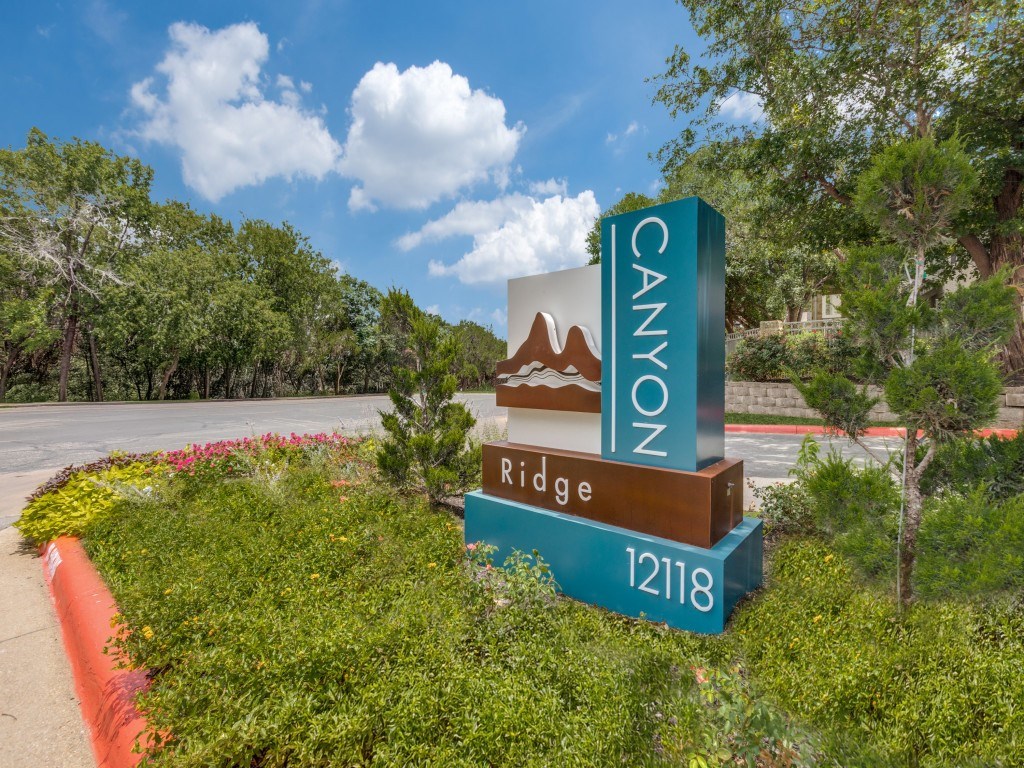 A sign for Canyon Ridge 12118 is in front of a green hedge.