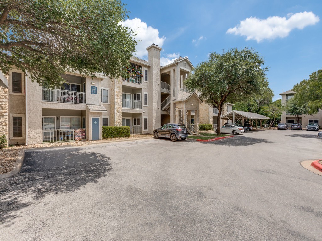 A parking lot in front of a building with cars parked.