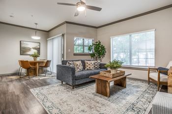 A living room with a grey couch, a wooden coffee table, and a rug at Canyon Ridge, Austin, TX, 78753