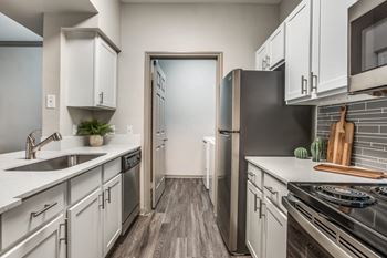 A modern kitchen with white cabinets and stainless steel appliances at Canyon Ridge, Austin, TX