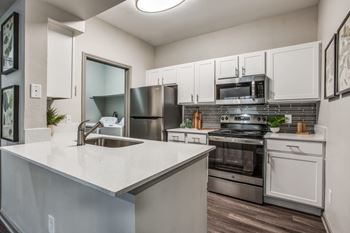 A modern kitchen with stainless steel appliances and white cabinets at Canyon Ridge, Austin, 78753