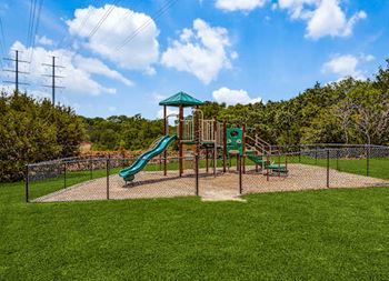 A playground with a green slide at Canyon Ridge, Austin, 78753 and a green roofed structure at Canyon Ridge, Austin, Texas