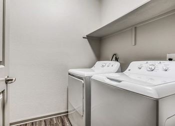 A white washing machine and dryer in a small laundry room at Canyon Ridge, Austin, TX