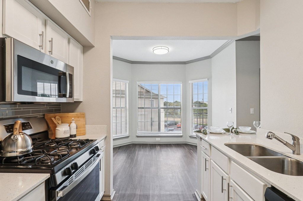 A kitchen with a stove, microwave, and sink.