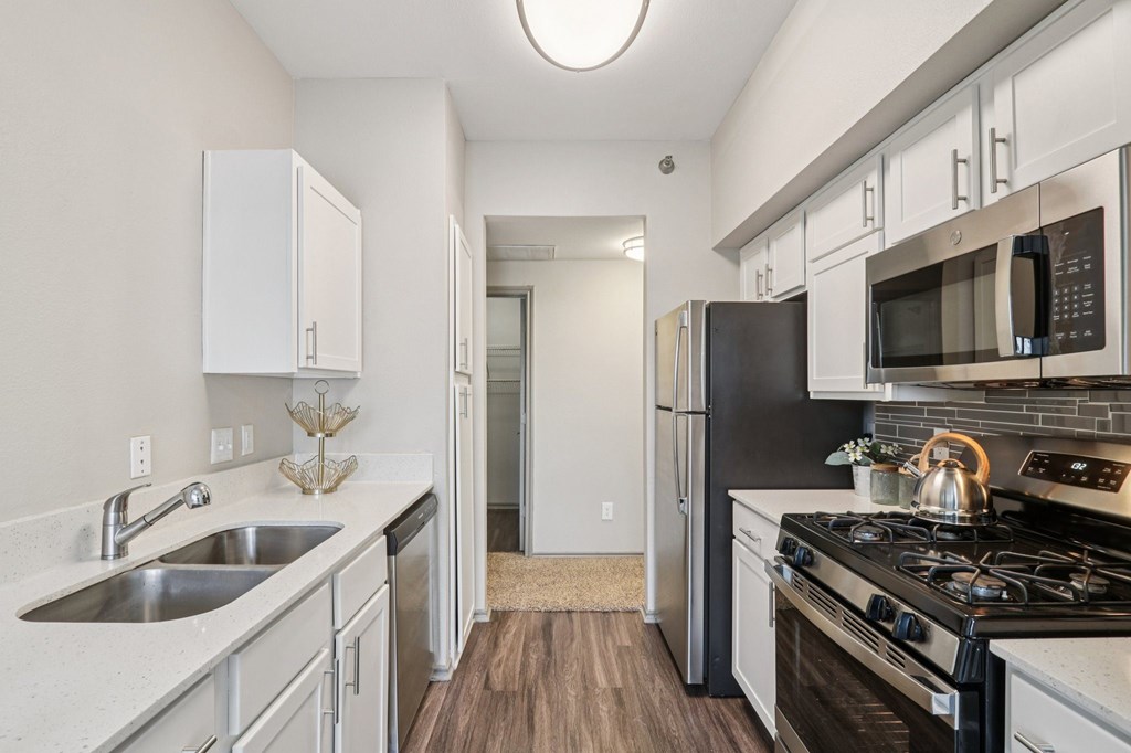 A kitchen with a black refrigerator and stove top oven.
