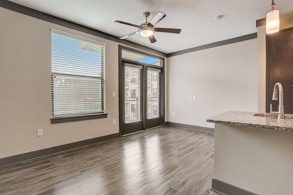 Pet-Friendly Apartments in Nashville, TN- Octave Apartments- Living Room with patio doors large windows wood style flooring and a ceiling fan