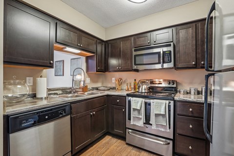 A kitchen with dark wood cabinets and stainless steel appliances.