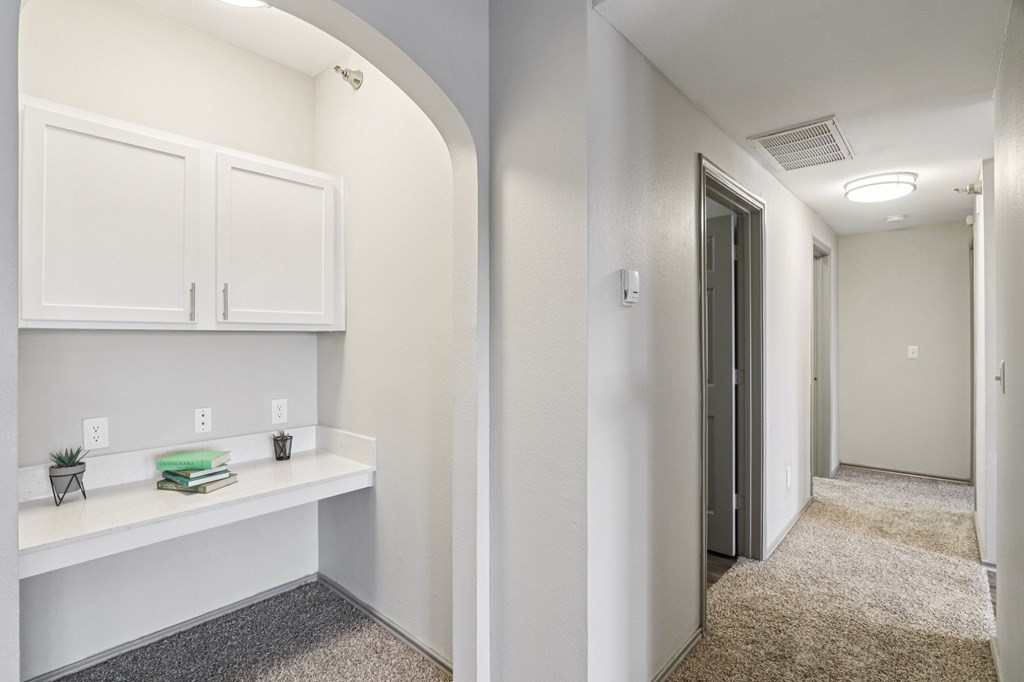 A hallway with a white cabinet and a grey carpet.