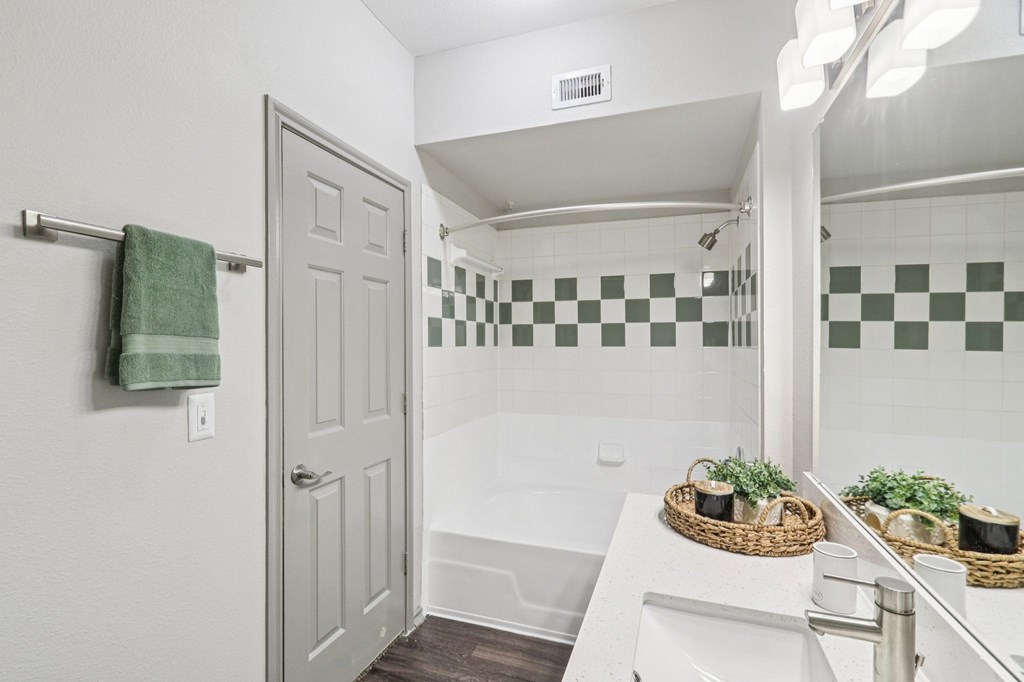 A bathroom with a white sink and a green and white checkered tile wall.