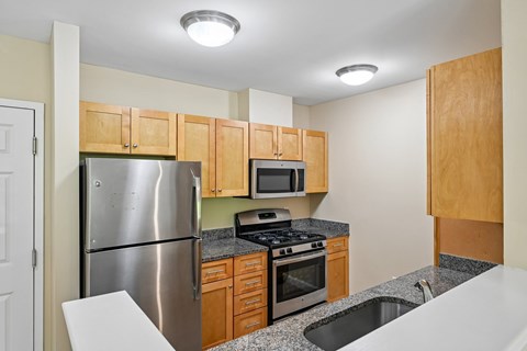 A kitchen with a stainless steel refrigerator, microwave, oven, and sink.