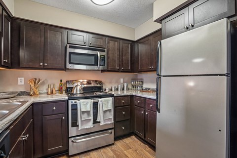 A kitchen with dark wood cabinets and stainless steel appliances.