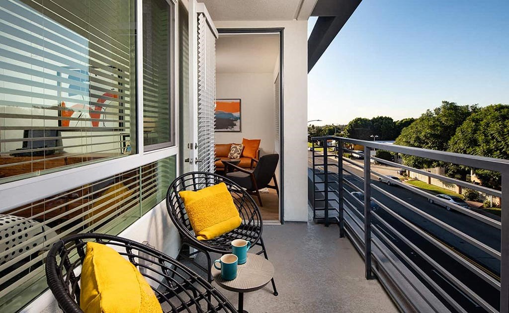 a balcony with chairs and a table and a view of the street