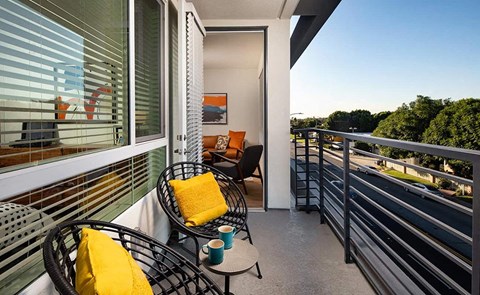 a balcony with chairs and a table and a view of the street