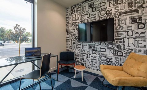 a living room with a tv and a desk with a laptop