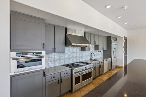 A modern kitchen with dark grey cabinets and stainless steel appliances.