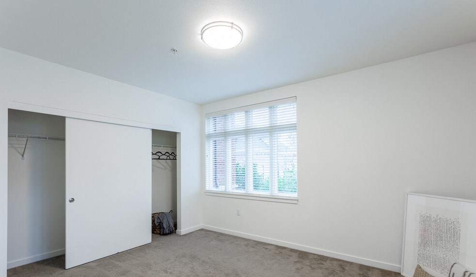 a bedroom with a large window and a closet