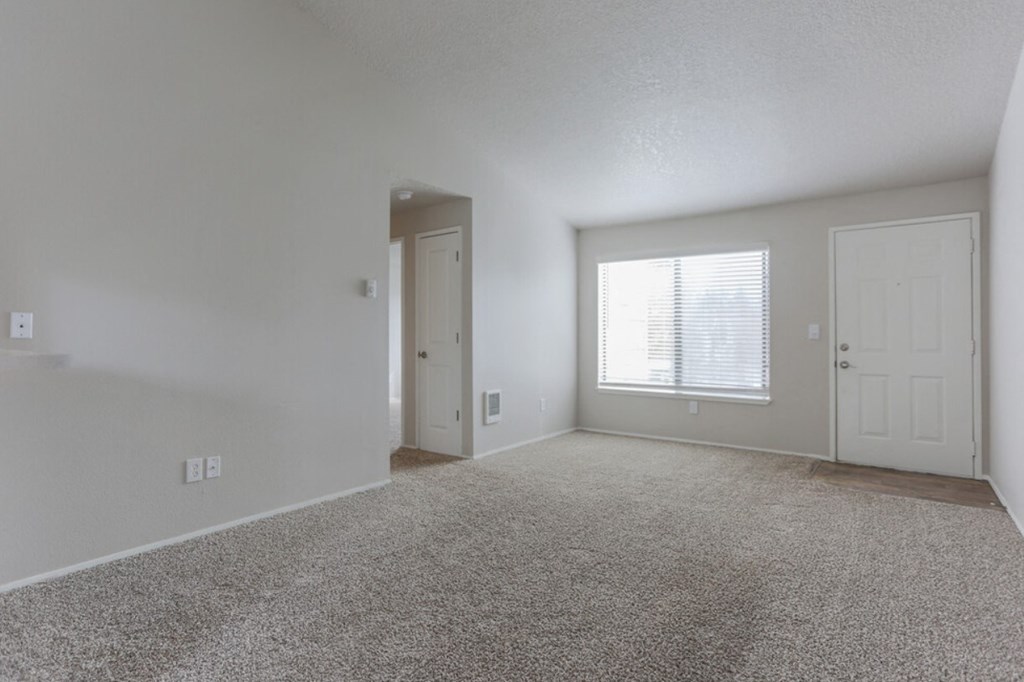 an empty living room with a window and a door