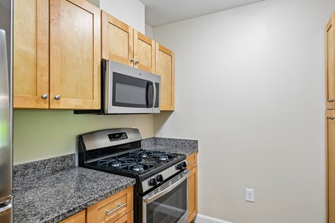A kitchen with a stove, microwave, and cabinets.