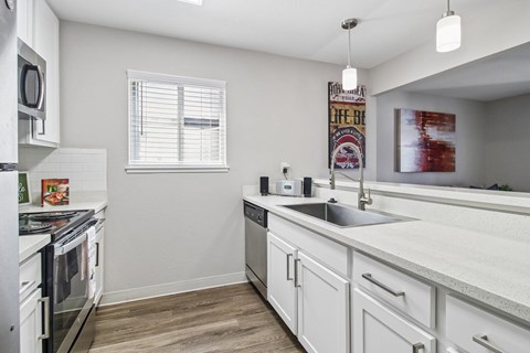 A kitchen with white cabinets and a wooden floor.