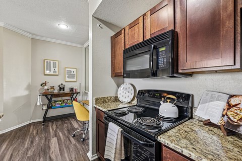 A kitchen with a black stove top oven and a black microwave above it.