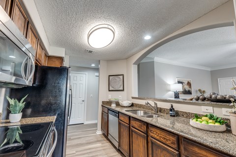 A kitchen with a black refrigerator and wooden cabinets.