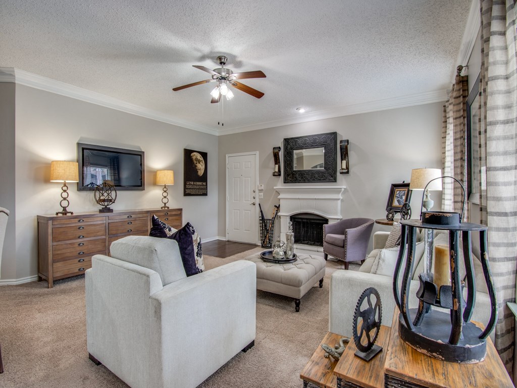 Two-Bedroom Apartments in West Houston TX - San Montego Apartments Spacious Living Room Area with Carpet Flooring, a Fire Place, Ceiling Fan, and Windows for Natural Light