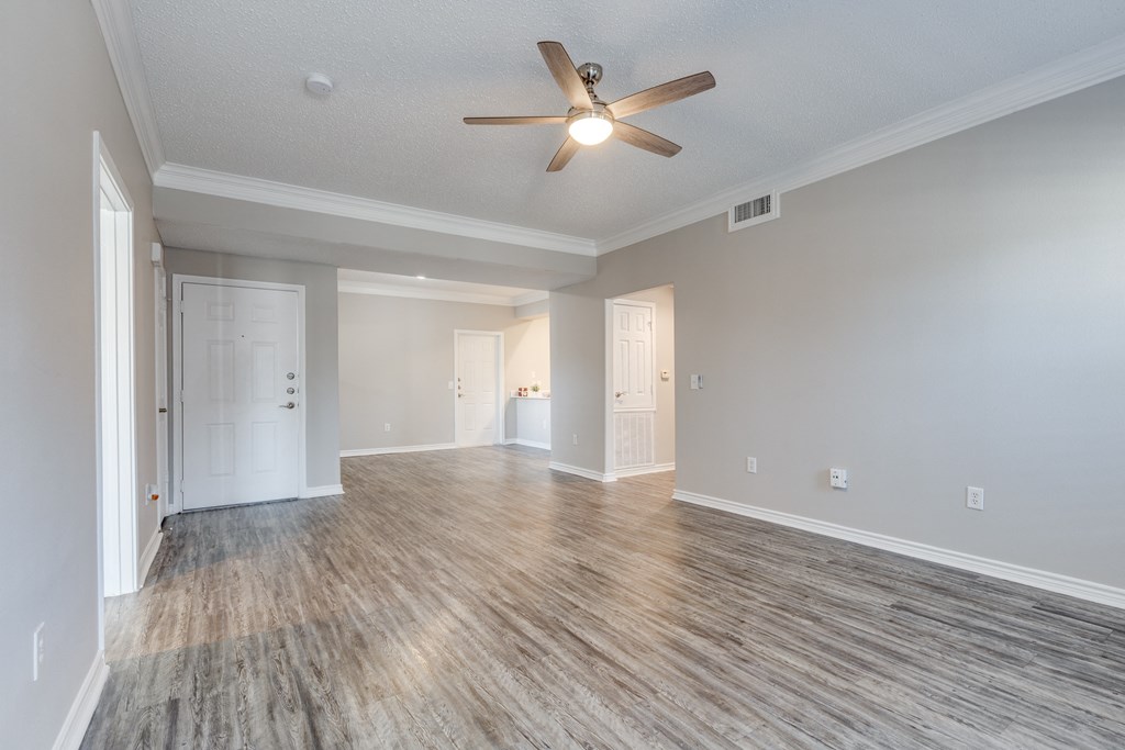 an empty living room with a ceiling fan