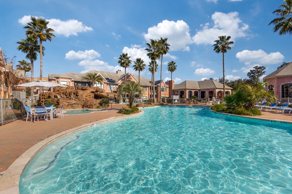 a large swimming pool with palm trees and buildings in the background