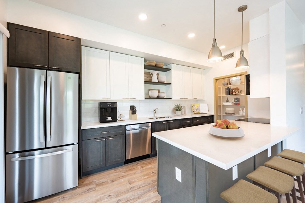 Scottsdale, AZ Apartments for Rent - The Sycamore at Scottsdale - Large Modern Kitchen with White Upper Cabinets, Darker Wood-Style Lower Cabinets, Silver Appliances, White Counters, with Large Cooking Area, Hanging Lights, Large Pantry, and Tile Backsplash