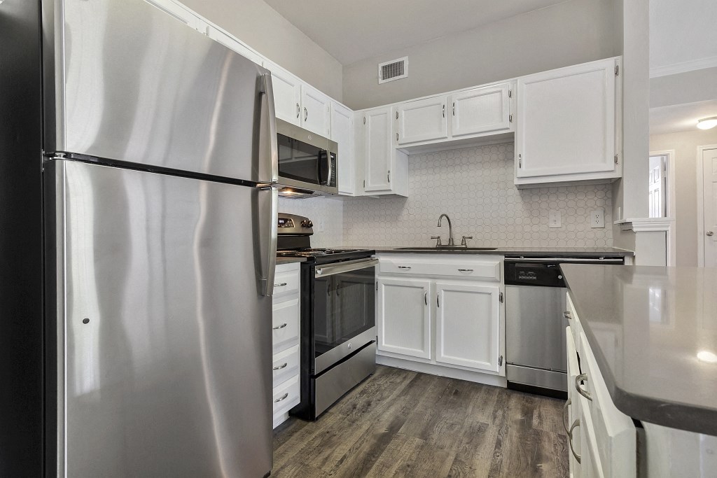Apartments for Rent in Plano, TX - Carrington Park Kitchen with Stainless Steel Appliances, White Cabinets, and White Tile Backsplash