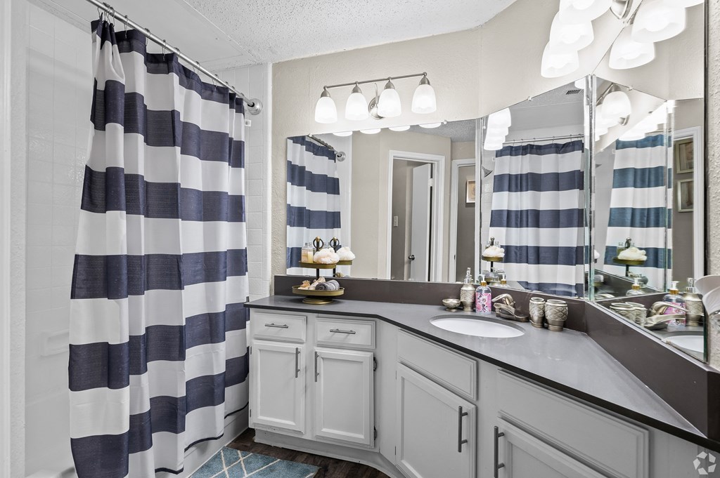 a bathroom with gray cabinets and a blue and white striped shower curtain
