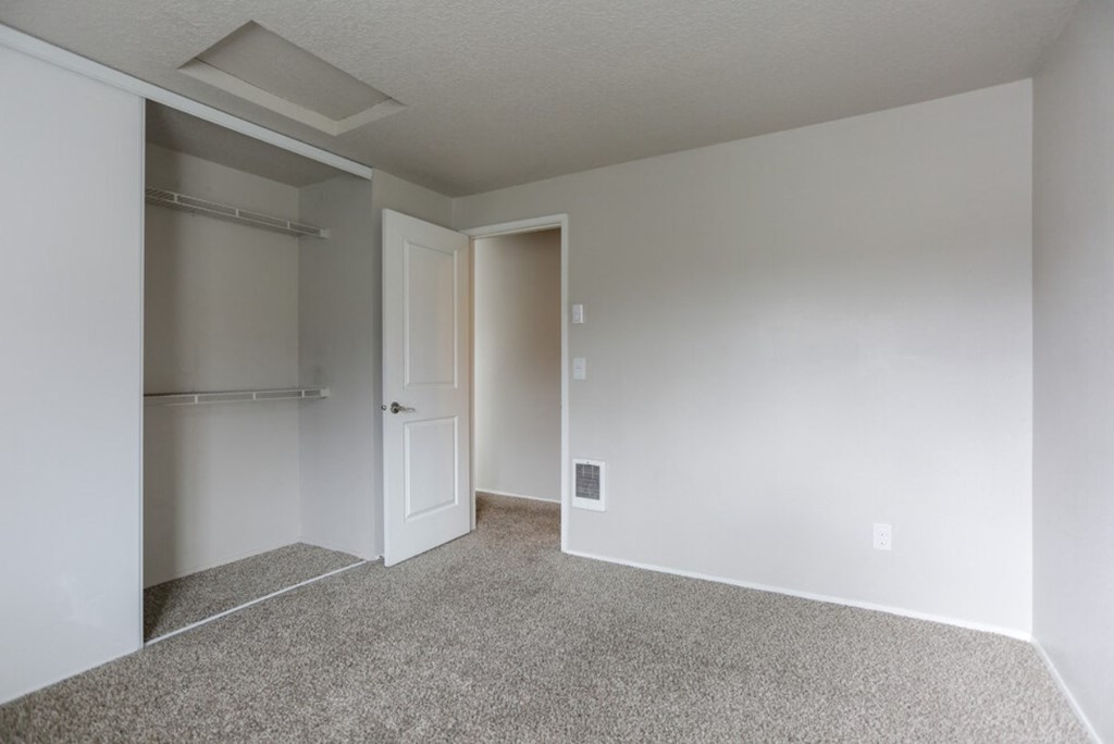 an empty bedroom with a closet and a door to the bathroom
